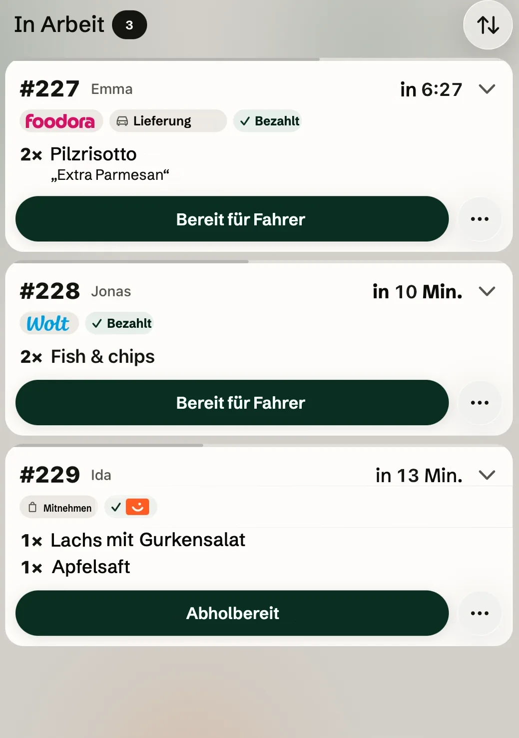 Die Spalte In Arbeit auf dem Küchenmonitor auf dem iPad im hellen Modus: Foodora-Lieferung 227, Wolt-Bestellung 228 und Bestellung 229 aus der App.