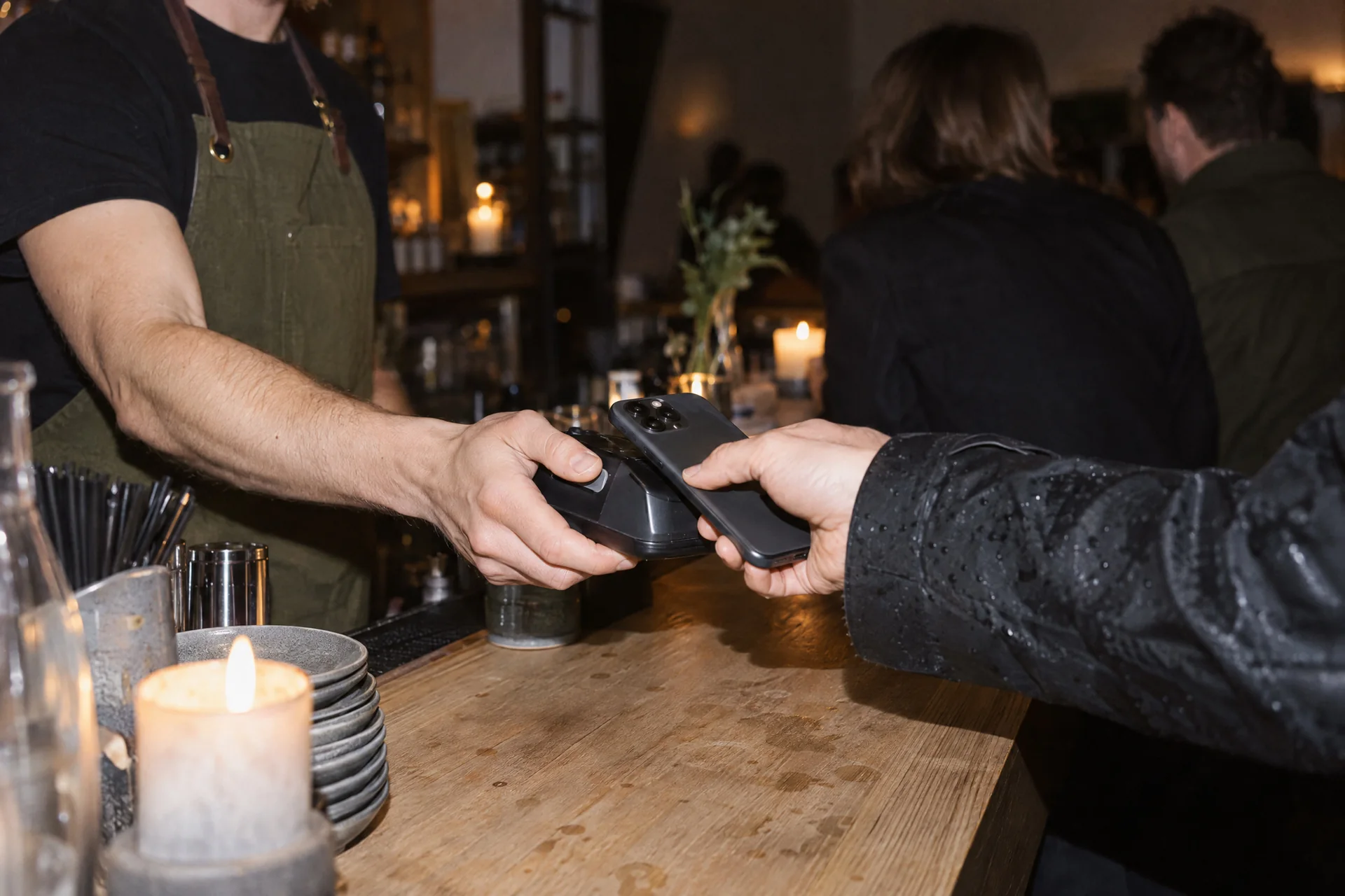 En gjest betaler med telefonen på kortterminalen over bardisken.